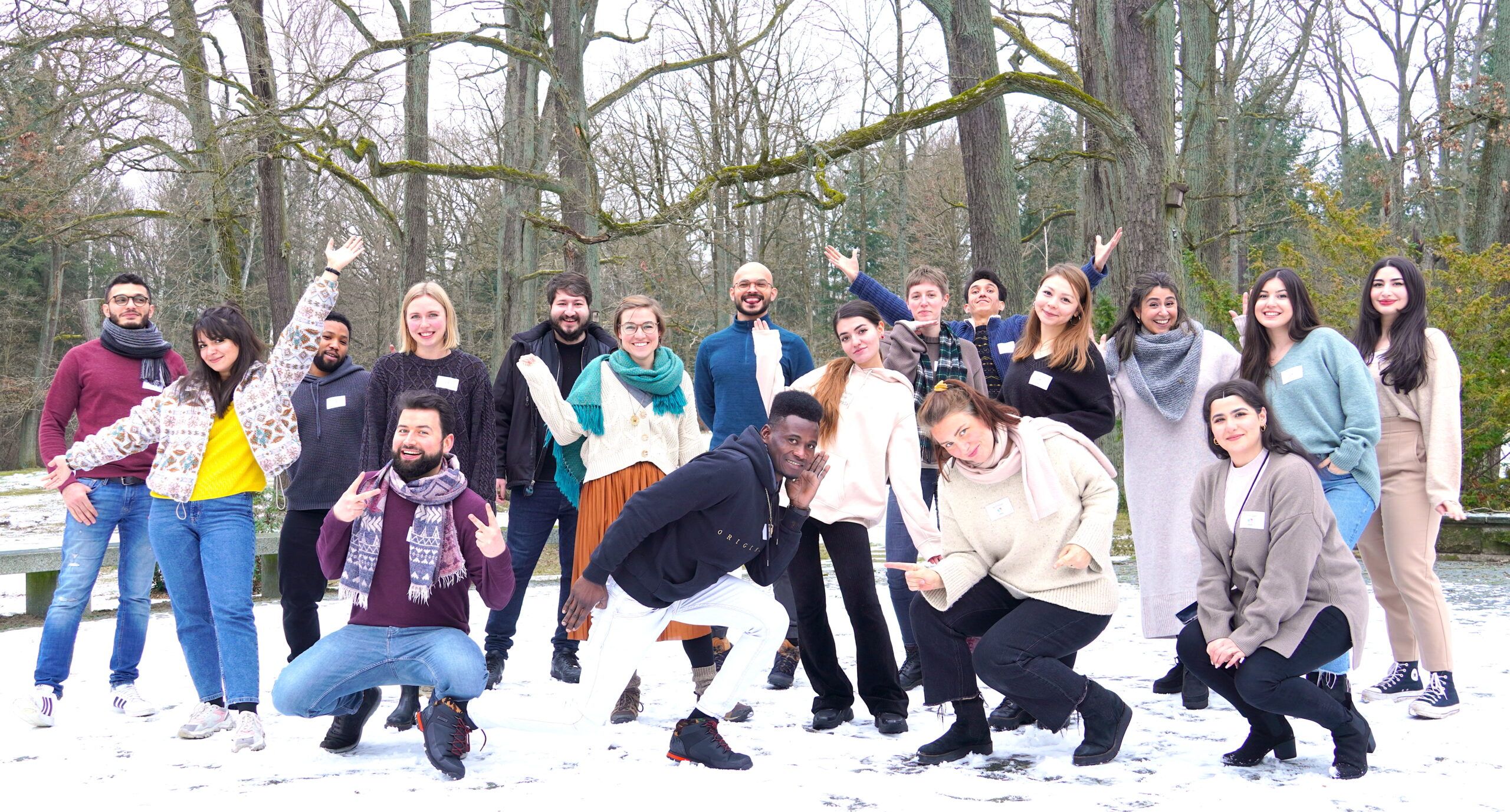 Das Team und eine zweite Gruppe posieren, lachen und winken in die Kamera in einer winterlichen Landschaft.